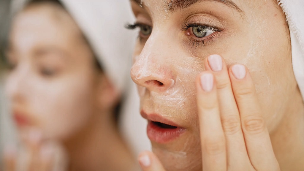 A woman applying cream to her face