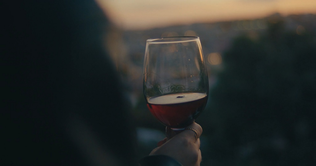 A person is holding a glass of red wine on the terrace