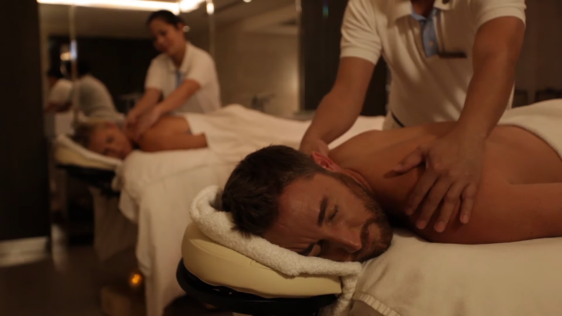 A Man and A Woman Receiving Back Massages from Spa Therapists in A Calm, Dimly Lit Room